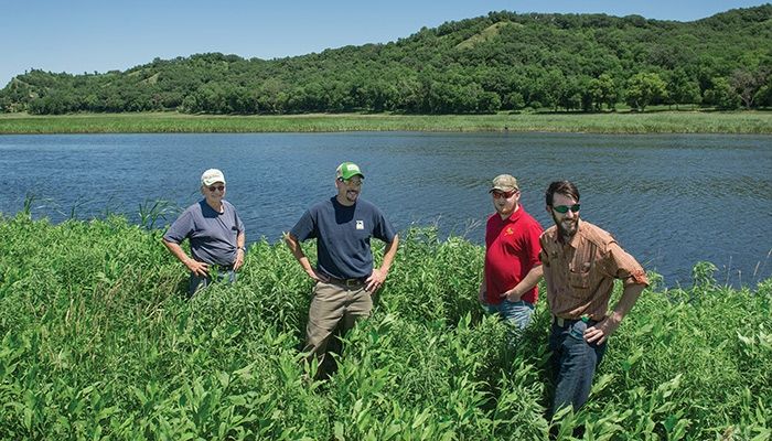 Goodman and his son Jon, second from left, inspect a 73-acre restored wetland on their farm north of Crescent with Pheasants Forever precision ag specialist Jeremy Biggs and wildlife biologist Nick Salick.