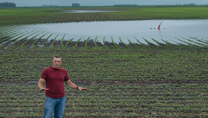 Pocahontas County Farm Bureau member Brian Dreith explains how heavy rains have left ponds in this field and threaten to drown struggling crops. PHOTO / GARY FANDEL