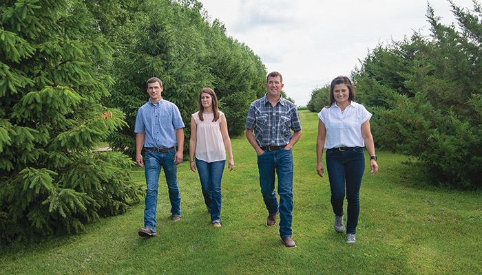 Bruce and Jenny Wessling, on the right, walk along a tree line with their daughter, Jolee, and her fiance, Austin Saddoris, on their Greene County farm near Grand Junction. 