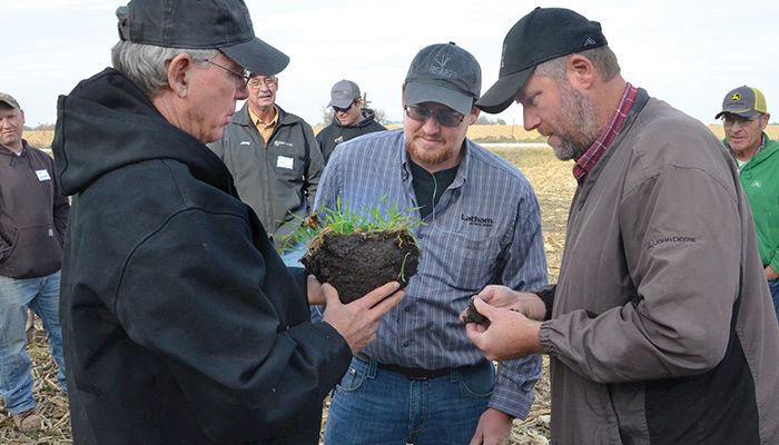 Mark Jackson, Mike Jackson and Jason Steele examine how cover crops are working underground to improve the soil at a Practical Farmers of Iowa field day on the Jacksons’ farm in late November. PHOTO / TOM BLOCK