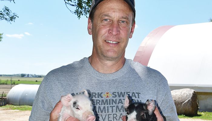 Rep. Chad Ingels of Randalia holds hours-old piglets on his hog and row crop farm in Fayette County.