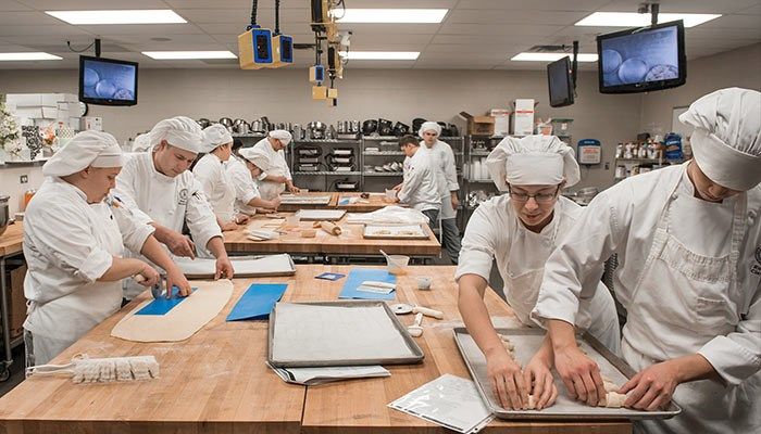 Culinary arts students at Kirkwood Community College roll and measure out pie crusts at their pastry class.