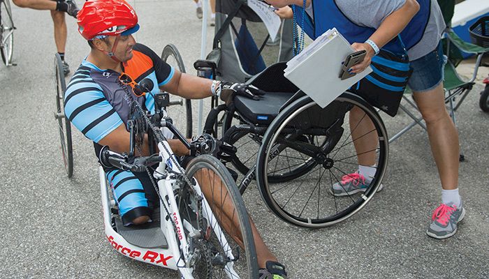 Adaptive Sports Iowa volunteer Kelli Kelderman checks in with cyclist Gerard Ah-Fook.