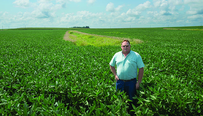 ??Iowa farmer Wayne Koehler stands by one of the terraces his father began building in the 1970s as a way to reduce soil loss.